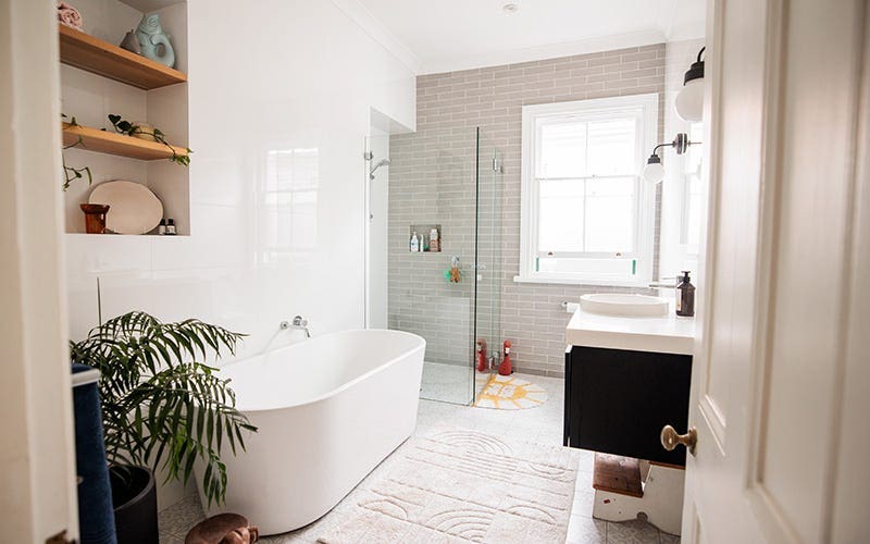 A bright bathroom featuring a white bathtub and a green plant for a fresh, inviting atmosphere.