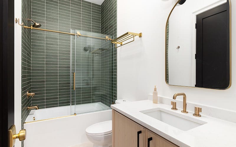 A contemporary bathroom with vibrant green tiles and chic gold fixtures, showcasing a blend of color and elegance