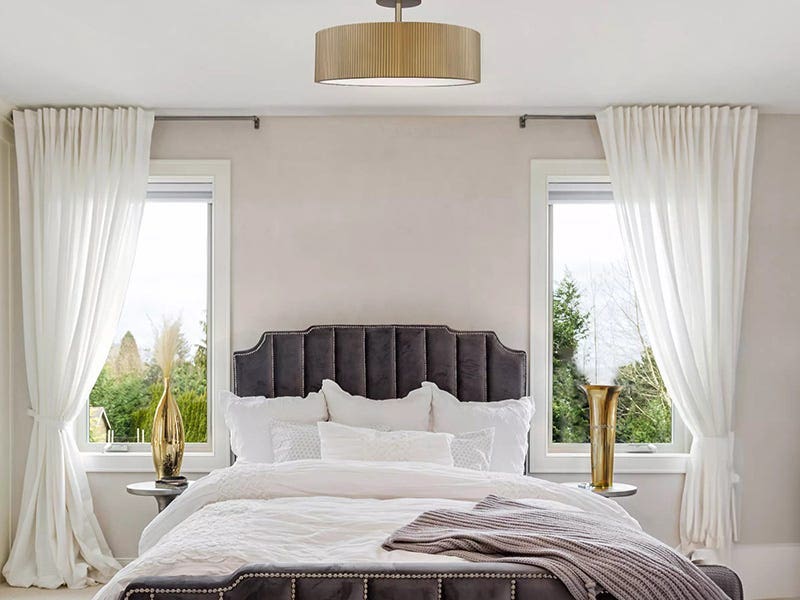 Chambre élégante avec un plafonnier en forme de tambour entre deux fenêtres