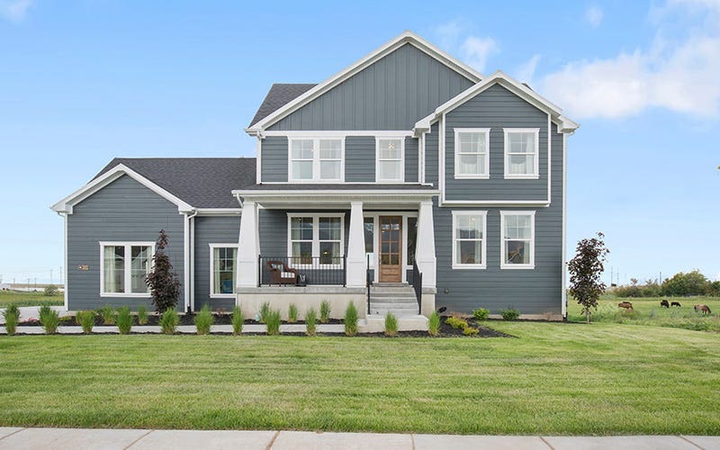 A gray house with a welcoming front porch and a landscaped front yard.