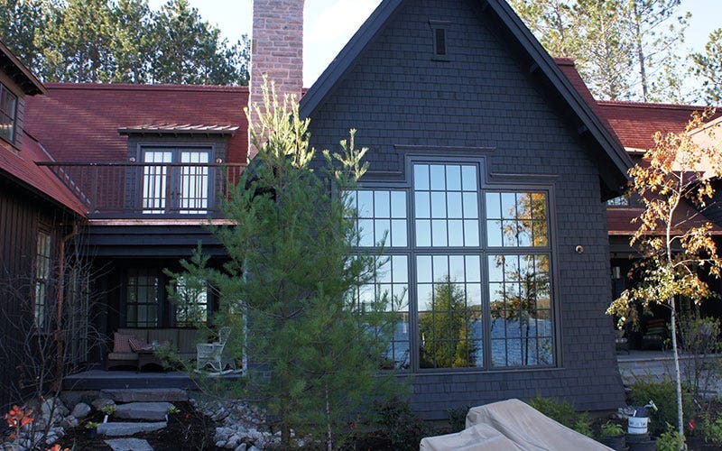 A striking black house topped with a bold red roof, set in a serene environment.