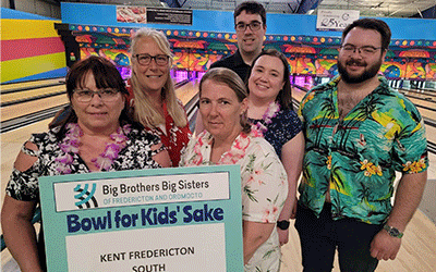Les membres de la communauté se réunissent, affichant un signe pour une collecte de fonds de bowling visant à soutenir les enfants dans le besoin