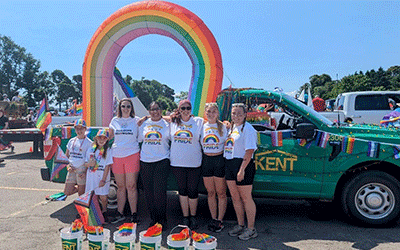Les membres de la communauté se réunissent devant un camion vibrant orné d'un arc-en-ciel, faisant la promotion de la course caritative 2slgbtqia+ Pride