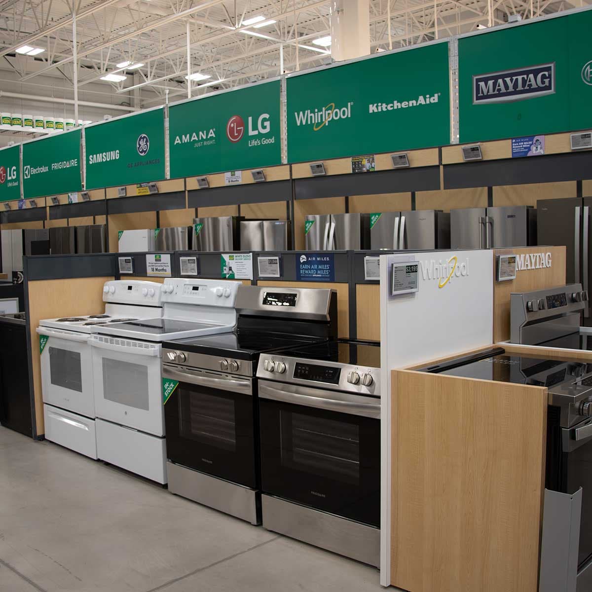 Appliance showroom display featuring ranges, refrigerators, and major brand signage inside a retail store