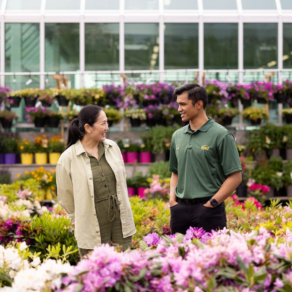 Customer speaking with a store associate in a garden center surrounded by colorful plants and flowers image