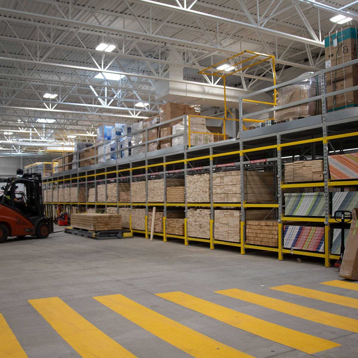 Indoor lumberyard area with stacked wood materials on industrial shelving and a forklift moving pallets image